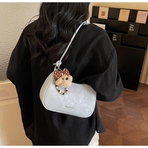 Close-up of gray hobo bag featuring a plush bear charm and printed brand logo details