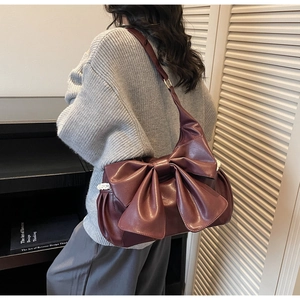 Detail of burgundy PU leather shoulder bag with bow and delicate lace trim on the side