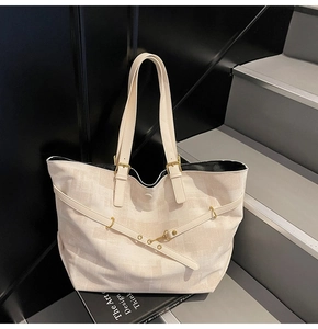 Detail view of large cream tote bag with textured finish and metal strap buckles