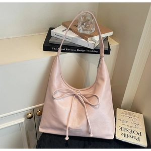 Close-up of a pink leather hobo bag featuring a bow tie detail and logo plaque