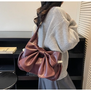Detail of burgundy shoulder bag featuring large bow design and white lace splicing