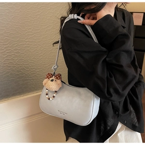 Detail view of a light blue leather shoulder bag with cute teddy bear charm