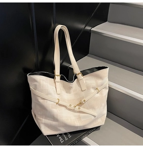 Detail of off-white tote bag with adjustable straps and gold metal hardware