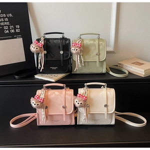 Detail showing four stylish glossy faux leather handbags in black, green, pink, and white