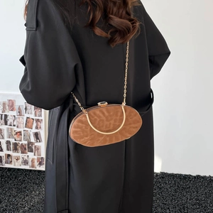 Detail of a brown animal textured oval clutch bag with gold frame and chain strap