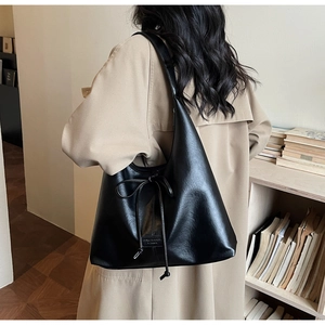 Detail of minimalist black tote bag with bow tie decoration and soft leather texture