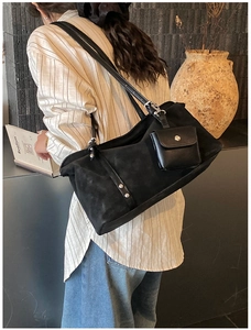 Detailed view of black suede tote bag with a mini pouch charm and silver rivet details