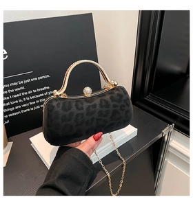 Detailed view of leopard print evening bag with gold metal handle and rhinestone clasp