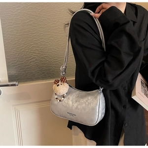 Detail of silver metallic hobo bag with teddy charm and brand logo on shoulder