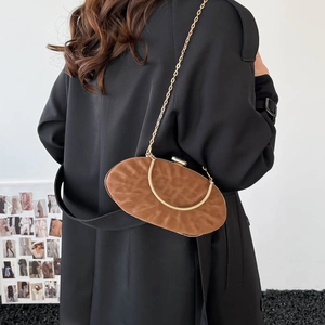 Close-up of brown textured leather shoulder bag with gold chain strap and metal handle