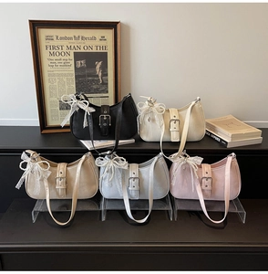 Détail du sac hobo avec nœud en dentelle, breloque perle et bandoulière ajustable