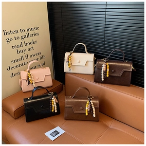 Detail view of five stylish handbags in various colors with colorful wooden beaded tassels