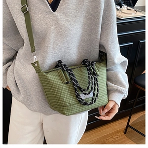 Detailed view of green plaid canvas handbag with dual rope handles and nylon strap