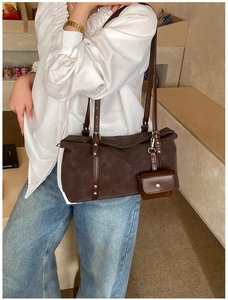 Detail of dark brown suede shoulder bag with adjustable straps and mini pouch