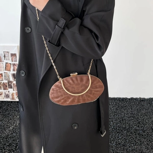 Detail of a brown pleated evening bag with gold metal handle and fine chain strap