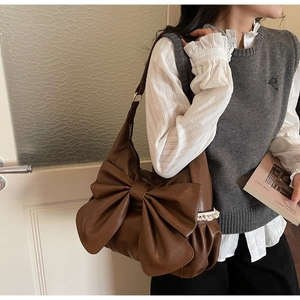 Detailed close-up of brown PU leather shoulder bag with bow and lace trim details
