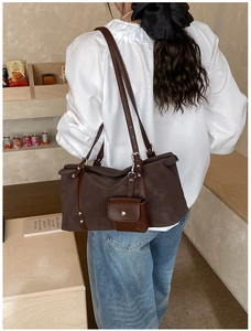 Detail of dark brown matte tote bag with rivet accents and a mini charm pocket