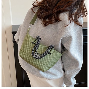 Detail of green plaid crossbody bag featuring woven rope handles and nylon strap