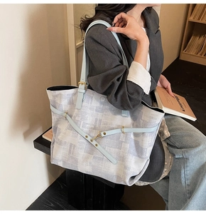 Detail of large tote bag showing light blue straps and grey geometric pattern in a cozy library