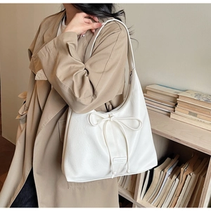Close-up of white bow detail and litchi texture on hobo tote bag shoulder strap