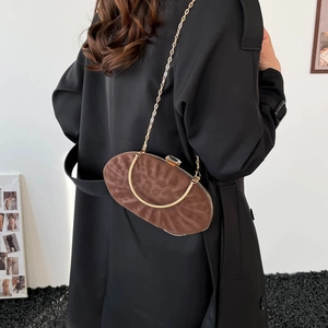 Detail of a brown leopard-print crossbody bag with golden chain and metal handle on black coat