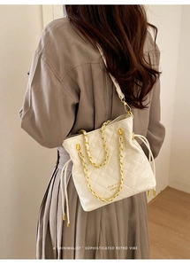 Model view of white quilted bucket bag with gold chain and PAN'TOR LONDON brand detail