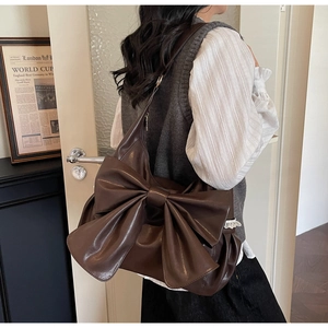 Detail of vintage brown shoulder bag with large bow and delicate lace trim
