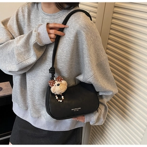 Detail of black dumpling shoulder bag with cute plush bear charm and knotted rope strap