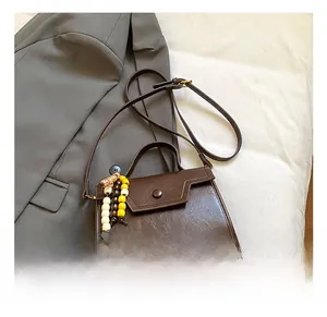 Detail of retro brown faux leather handbag with wooden bead charm on a grey blazer
