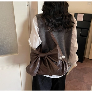 Detail of vintage brown hobo bag featuring large bow and white lace trim accents