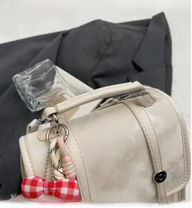 Detail of off-white faux leather handbag featuring marble texture and a bow charm
