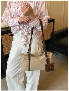 Detail of beige suede shoulder bag with dark brown strap and detachable mini pouch