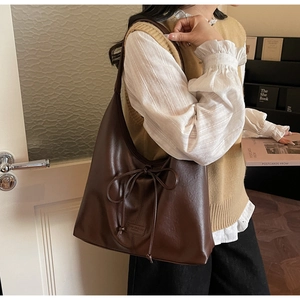 Detail of deep brown Hobo bag featuring a drawstring bow and textured faux leather surface