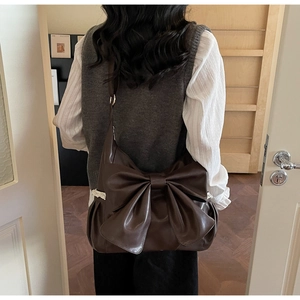 Detail of vintage coffee shoulder bag featuring bow design and delicate lace trim