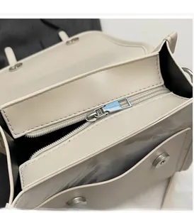 Close-up of smooth metal zipper and magnetic buckle on beige faux leather tote bag