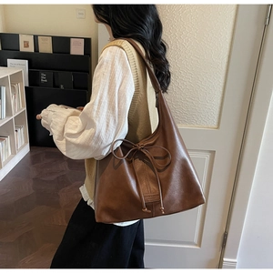 Close-up of brown vintage tote bag with bow drawstring detail and wide shoulder strap