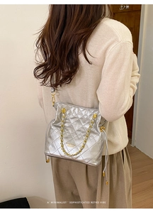 Silver quilted shoulder bag with gold chain strap and brand logo shown on model
