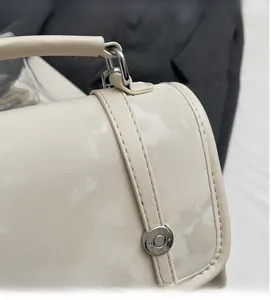 Detail of creamy white tote with marble texture, fine stitching, and silver round lock
