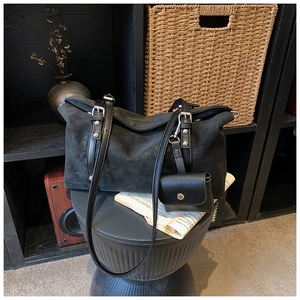 Detail of black matte suede tote bag featuring silver buckles and small hanging purse