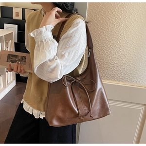 Detailed view of brown leather tote bag with a decorative bow and zipper closure