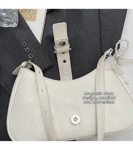 Détail du fermoir magnétique sur sac demi-lune crème avec nœud en dentelle et perle