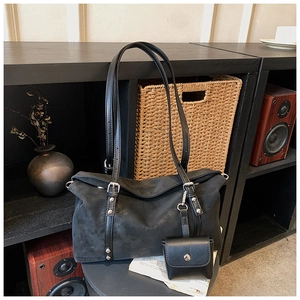 Detail of black matte tote bag with silver metal buckles and mini pouch attachment