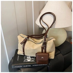 Detail of beige suede tote bag featuring brown leather straps and metal rivet accents