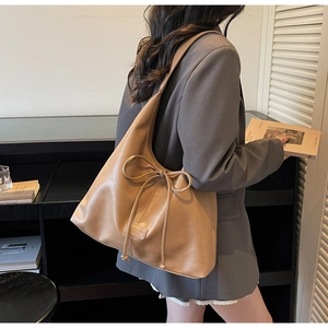 Detail of camel PU leather tote bag with elegant bow drawstring and logo patch