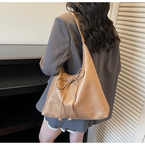 Detail of a brown PU leather hobo shoulder bag with stylish bow drawstring decoration