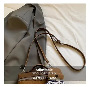 Detalle de la correa ajustable en bolso bandolera de cuero marrón con colgante de oso
