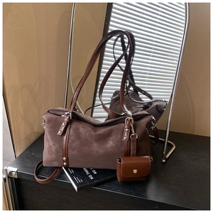 Detail of dark brown suede shoulder bag featuring metal rivets and mini accessory pouch