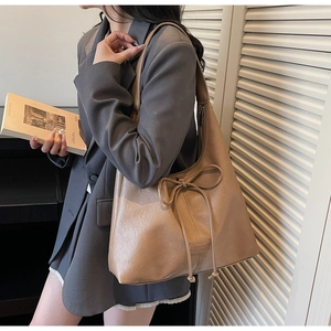 Detail of khaki PU leather tote bag featuring a decorative bow drawstring and spacious interior