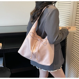 Detailed view of light pink leather tote bag with elegant bow decoration and smooth finish