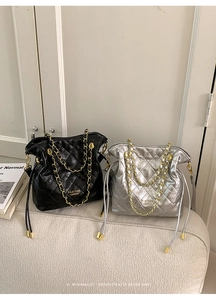 Detail of quilted bucket bags in black and silver with gold chain and drawstring straps